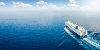 Vessel on open water sailing into calm seas and blue skies