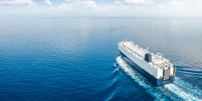 Blue and white ship at sea with blue sky and clouds