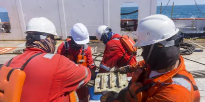 Four seafarers on deck installing an anchor panel
