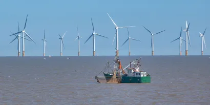 Fishing vessel at sea with offshore wind farm in background
