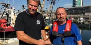 Ben Squires and Paul Reed shaking hands at a marina