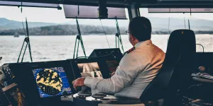 A male ship's captain sits looking out to the distance